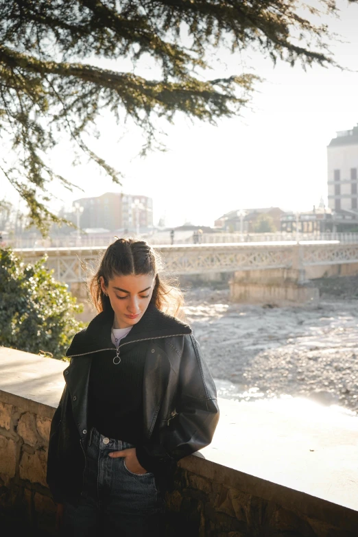 a woman standing near a river and a bridge