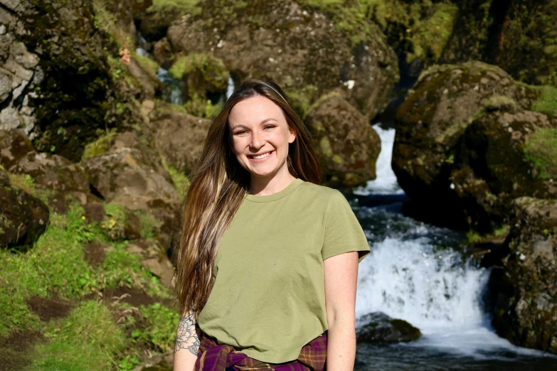 woman in green shirt near a river and rocks