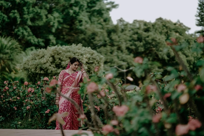 woman in floral dress standing near bushes with flowers