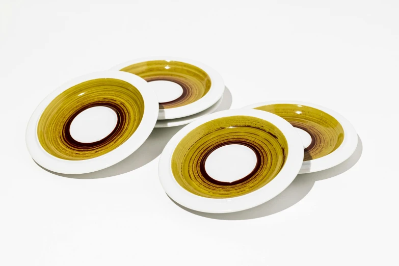 four yellow and white plates with a circular design