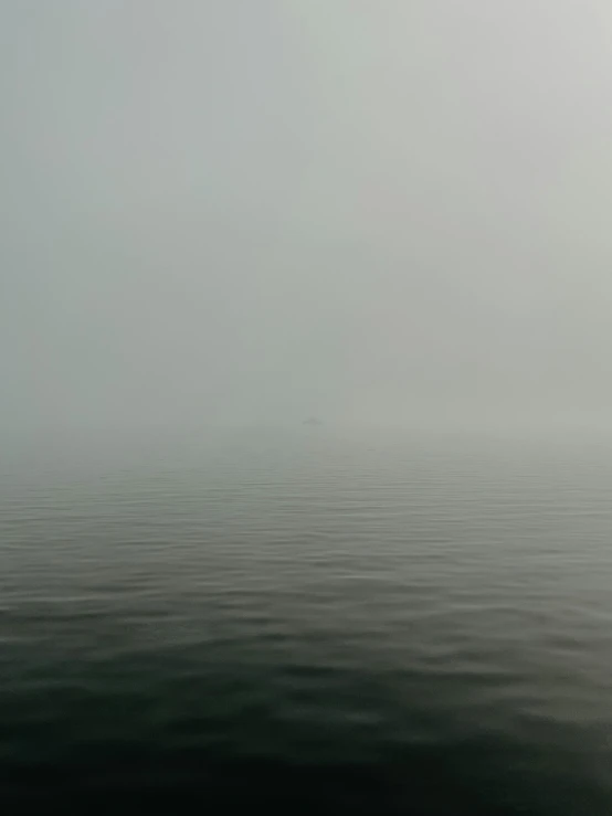 a large body of water in the middle of a foggy sky