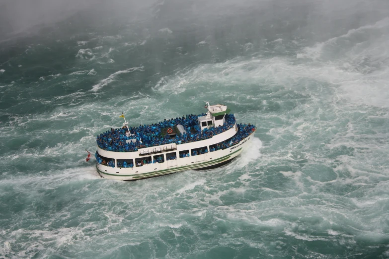 an aerial view of a boat with passengers traveling on the rapids