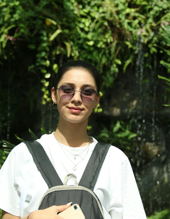 a woman in white shirt and sunglasses carrying a bag