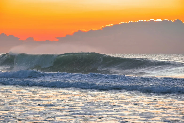 a surfer rides the waves on his surfboard at sunset