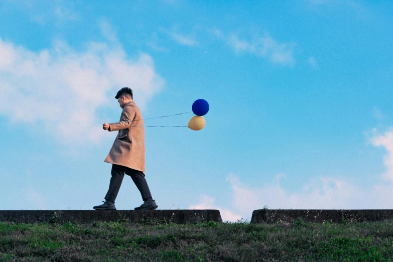 a man flying kites over a green hillside under a blue sky