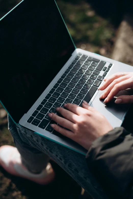 someone using a laptop outside on the grass