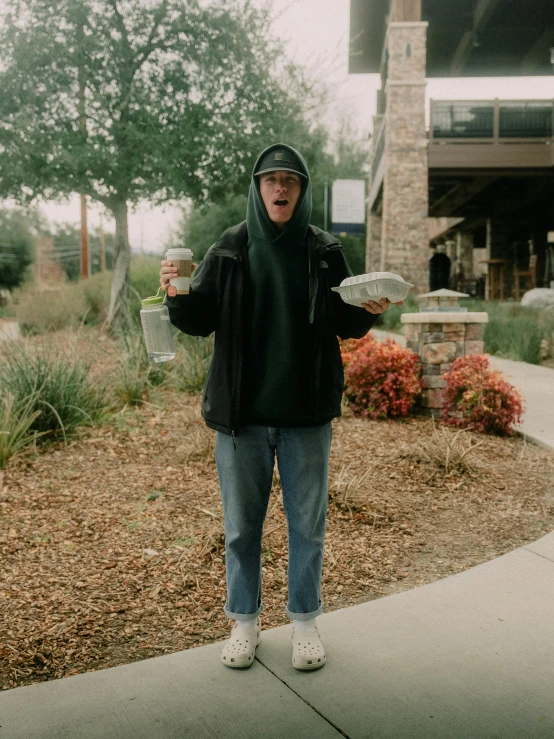 a man holding a drink near a brick building