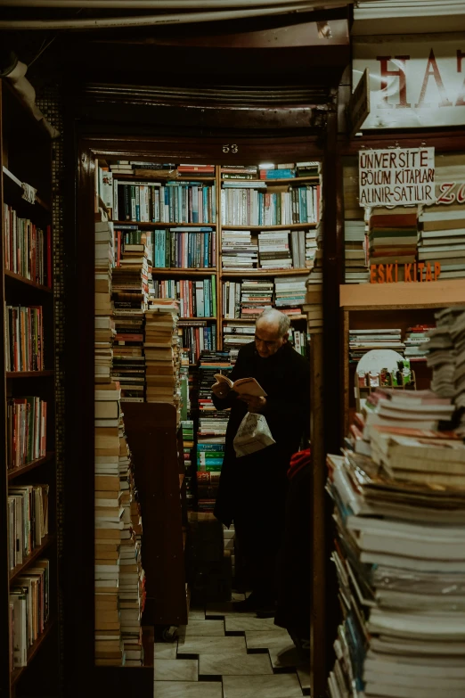 a man sitting down in front of a bookshelf
