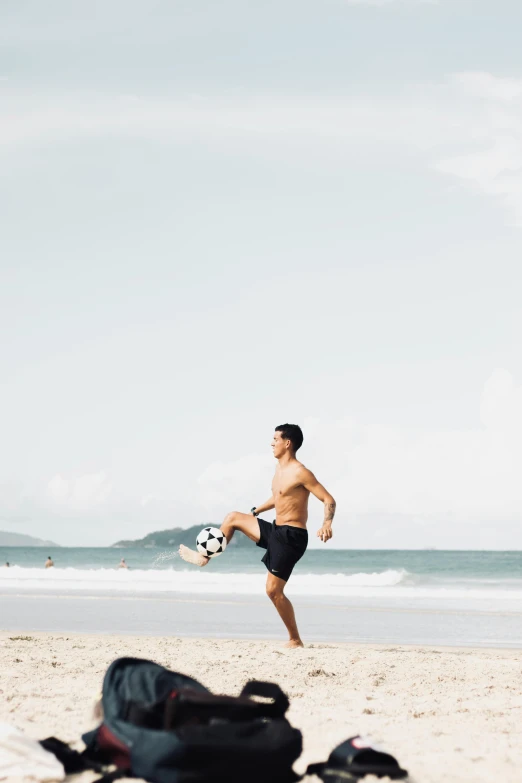 a person kicking a soccer ball near the ocean