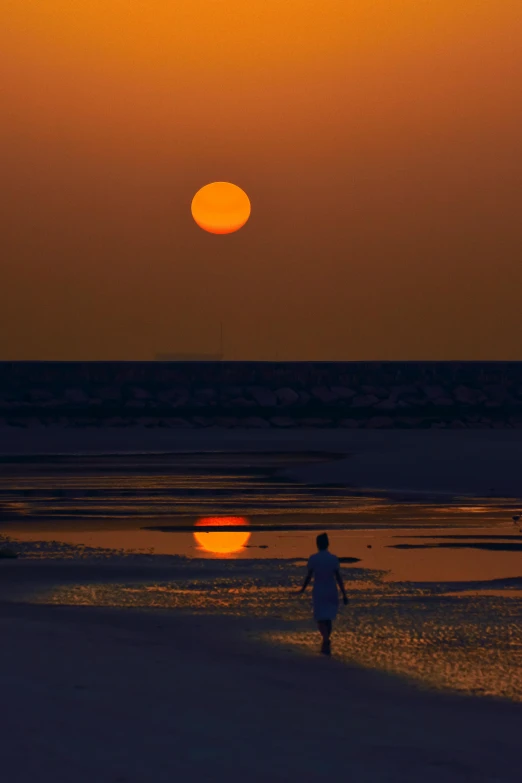 a person walking on the beach at dusk