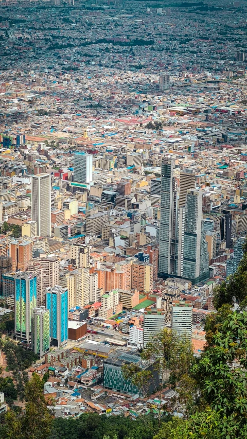 a city from a hill top with trees and mountains