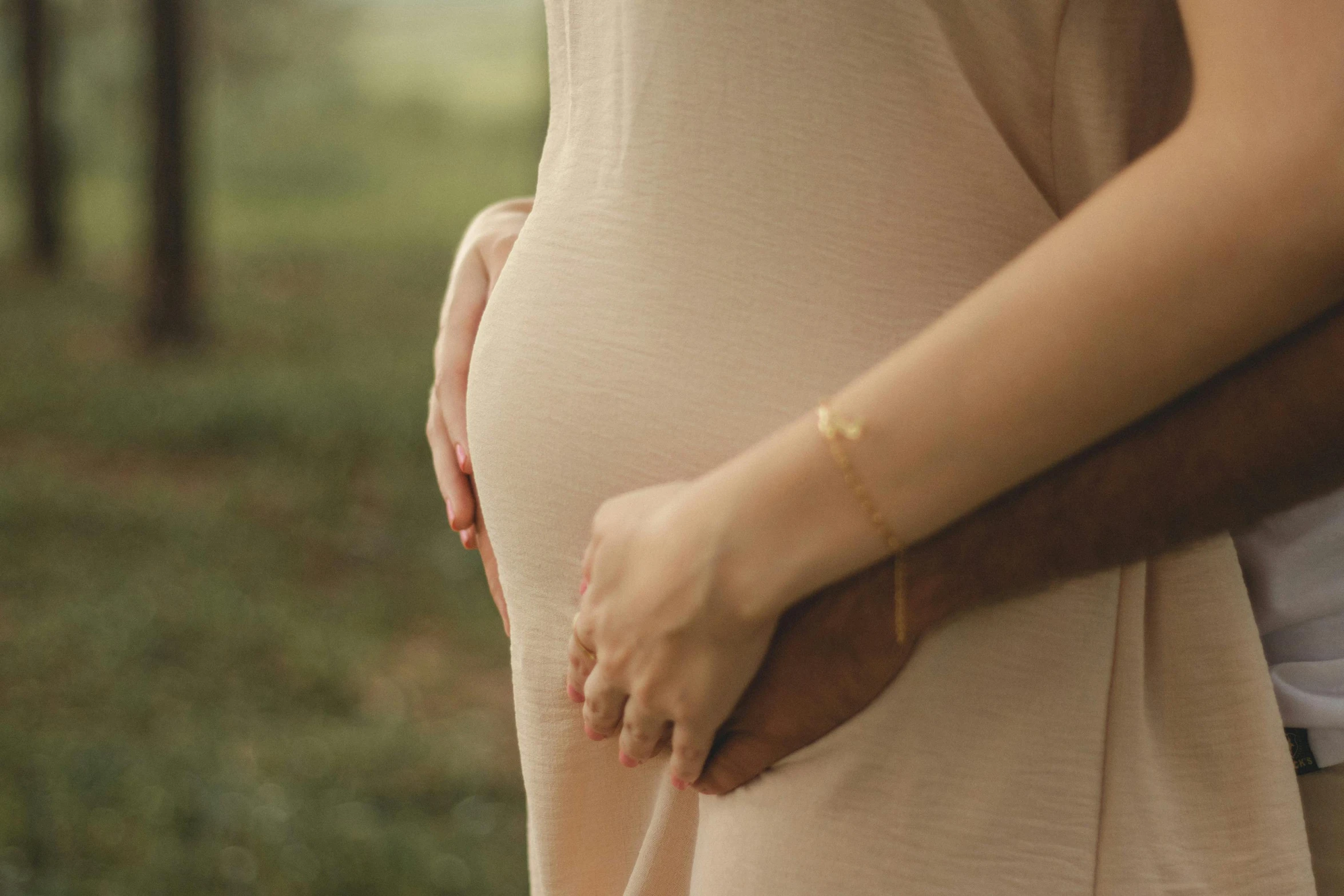 a pregnant couple holding each other, and one holding her belly