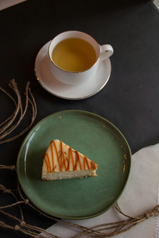 a tea cup sitting next to a plate with a piece of cake on it