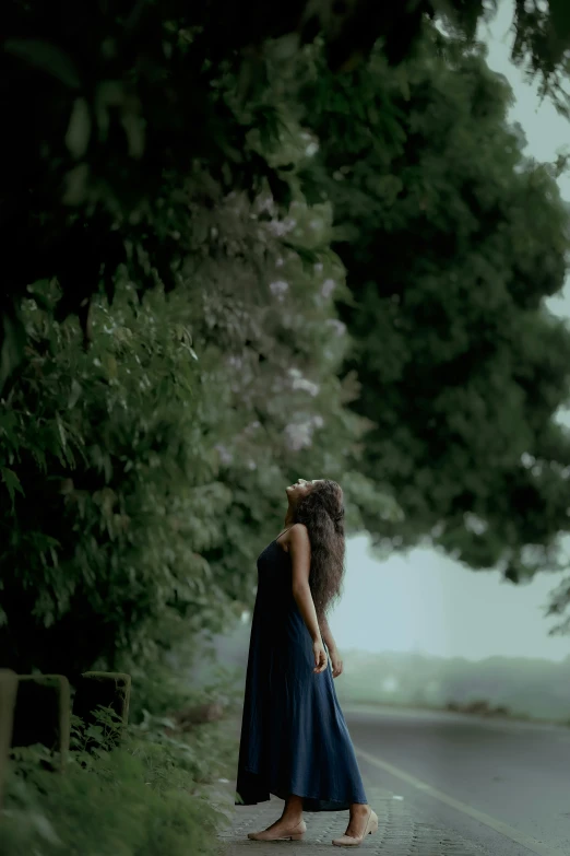 a woman wearing a long dress walks down a road