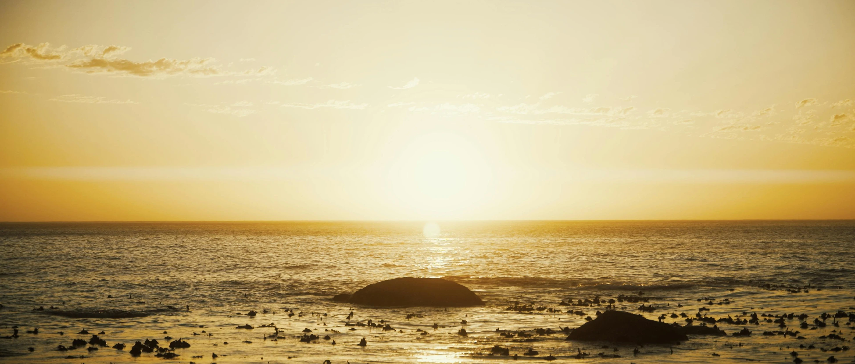 a sunset over a body of water with rocks