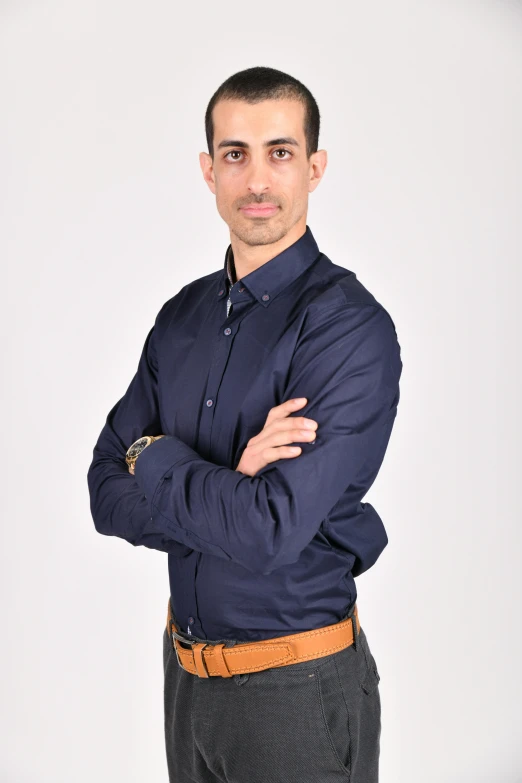 a man poses for a pograph while wearing a blue shirt and brown pants