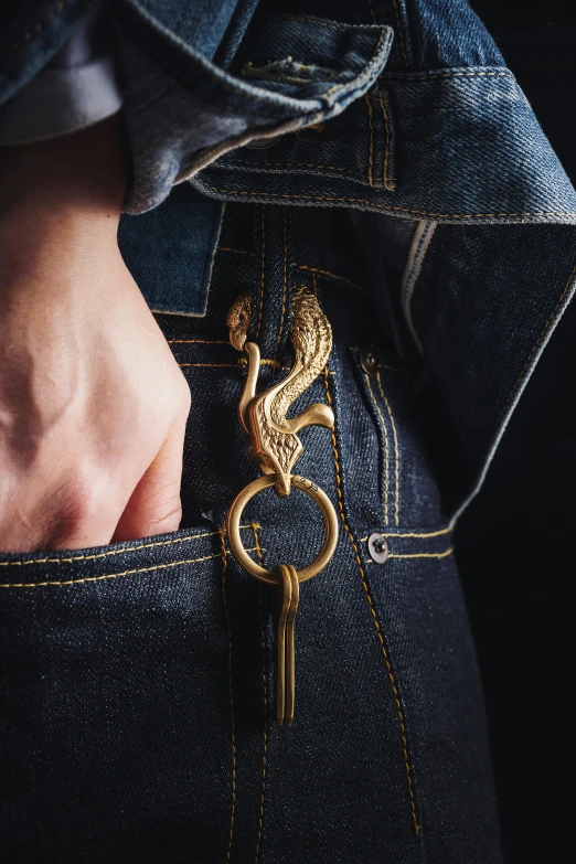 a man's pocket with a gold keychain in his jeans