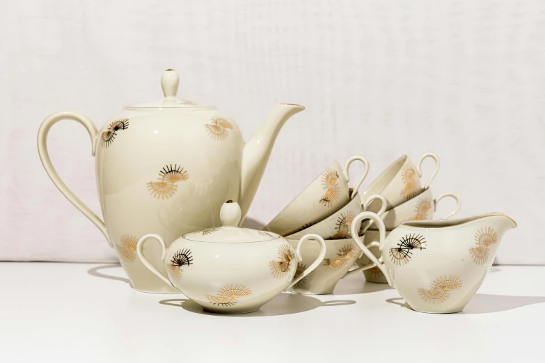 a tea pot and cups with a tea strainer