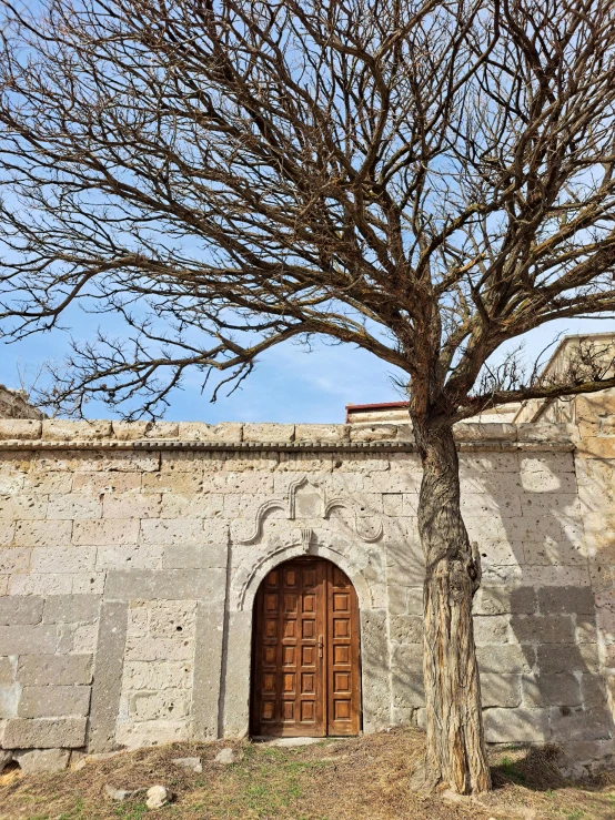 a stone building with an entrance and tree with no leaves