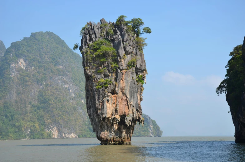 a large rock island stands out in the water near an island that is on one side of the water