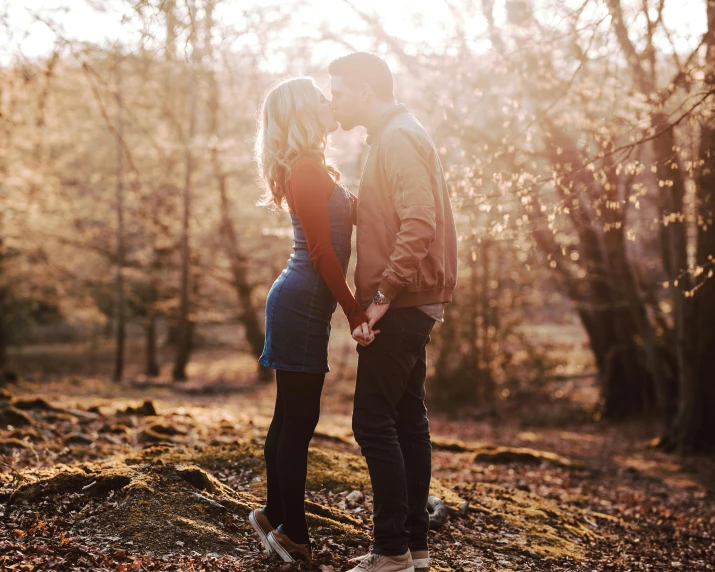 a couple poses together for a picture while standing in a forest with bare trees