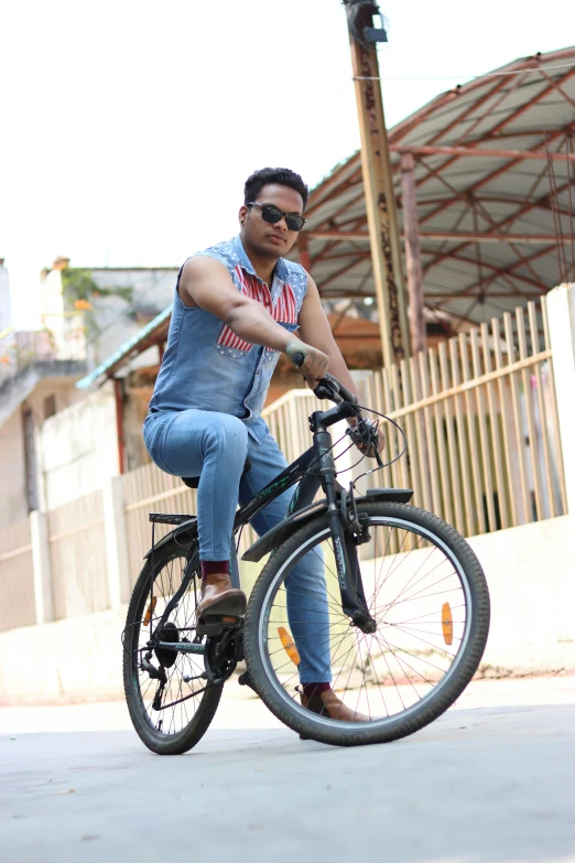 a man riding a bike with blue jeans and sunglasses