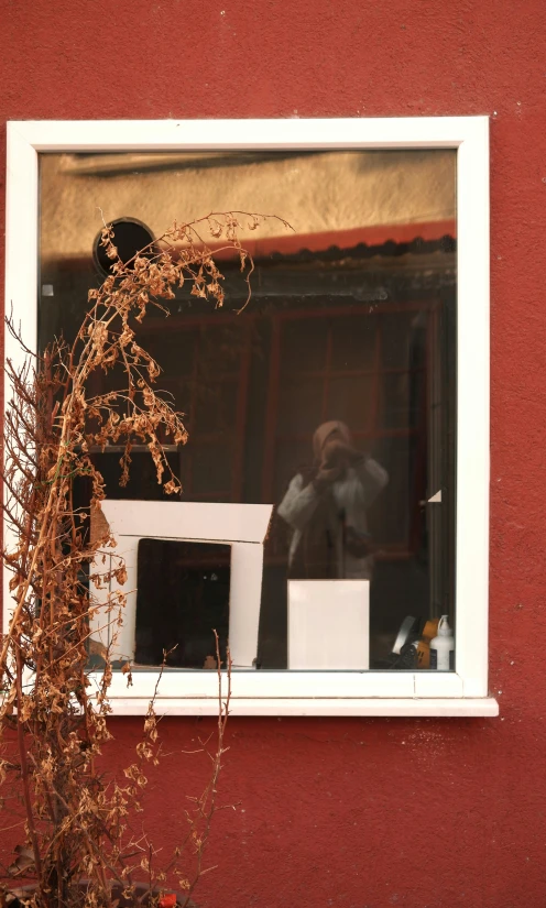 a man is reflected in a mirror behind a window