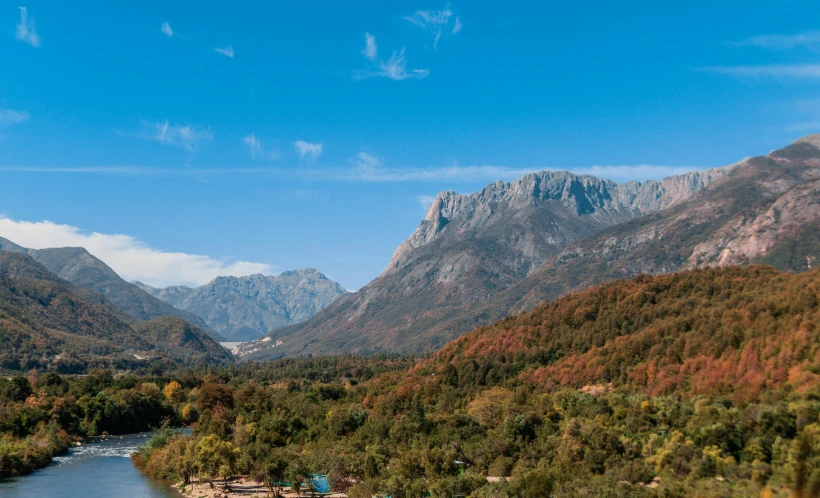 a river flowing through a valley with mountains behind it