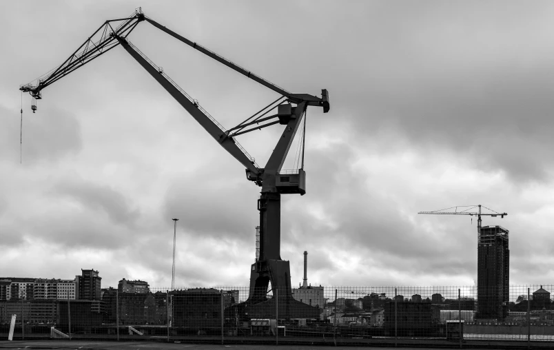 a very tall crane on the ocean by a city