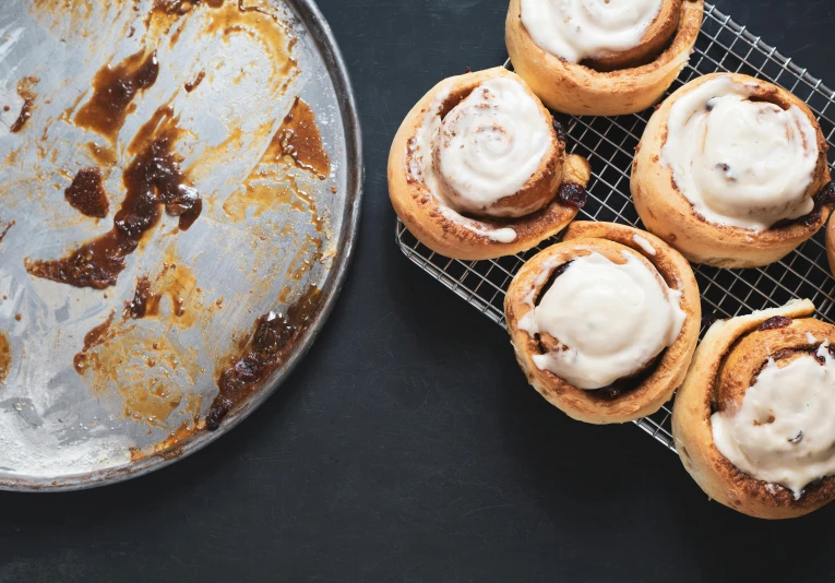 several cinnamon rolls sit on a cooling rack