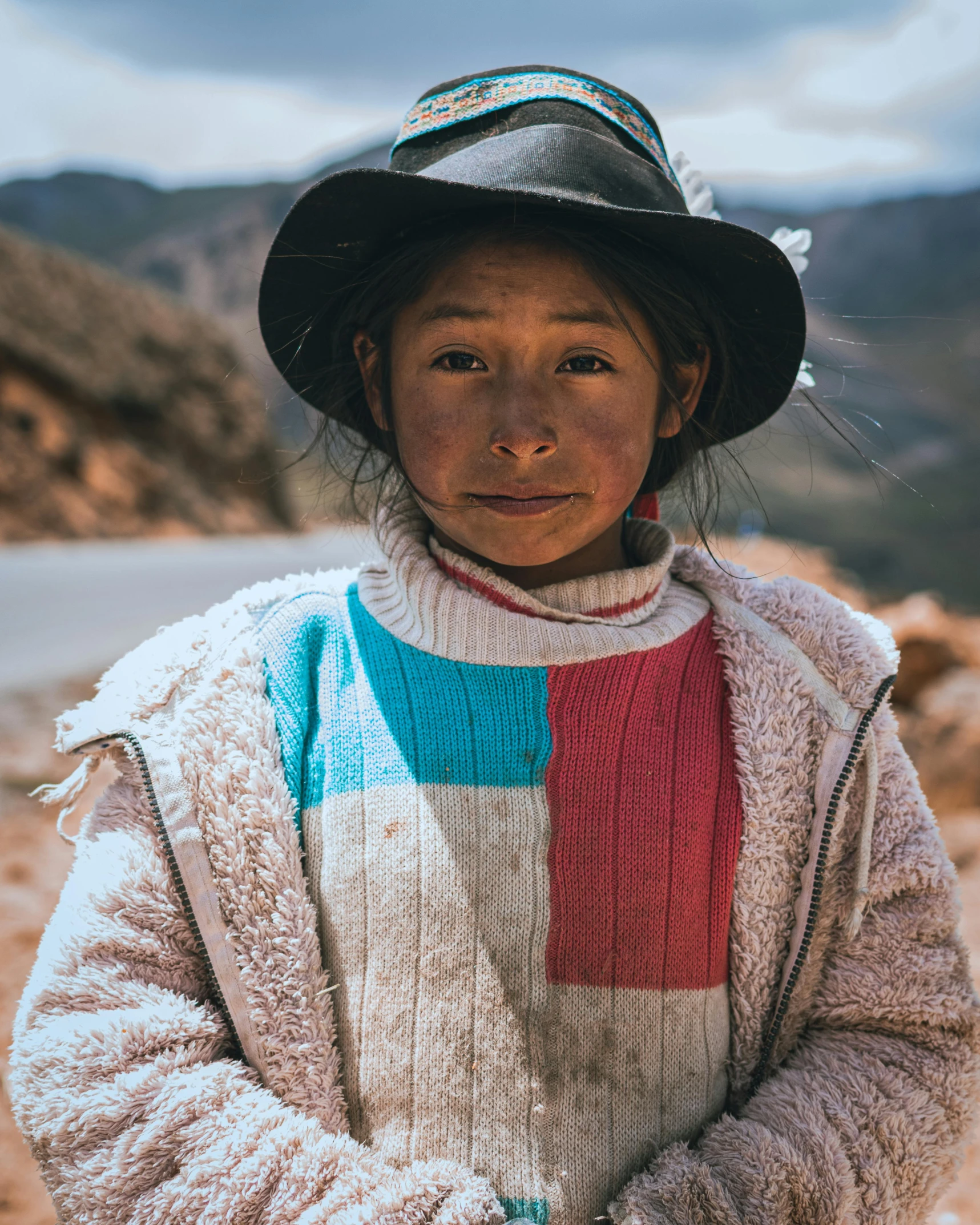 a girl wearing a hat and sweater with hands folded