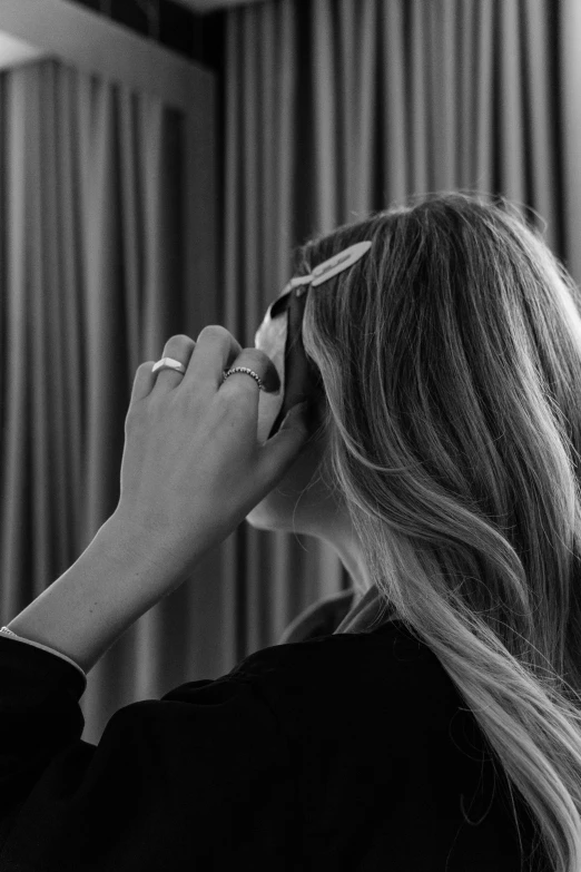 a woman putting on her hair while in front of a mirror