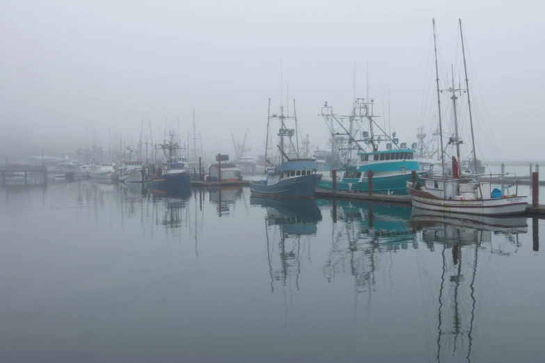 several boats are docked in a foggy bay