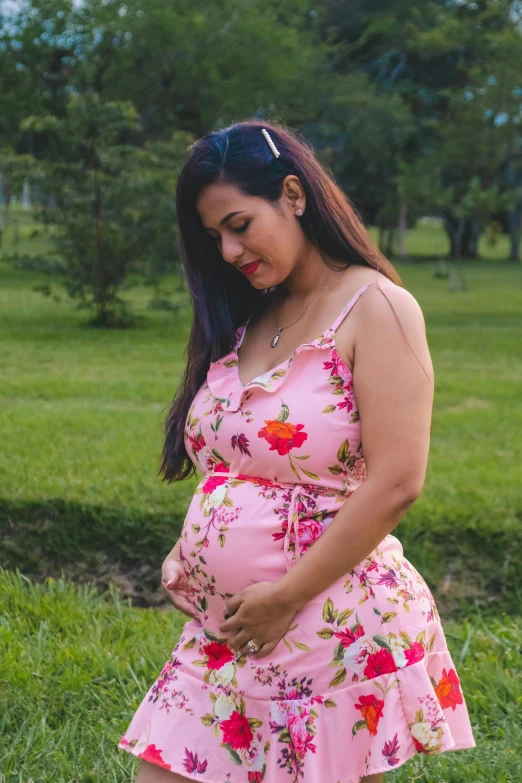 a pregnant woman holding her belly in a field