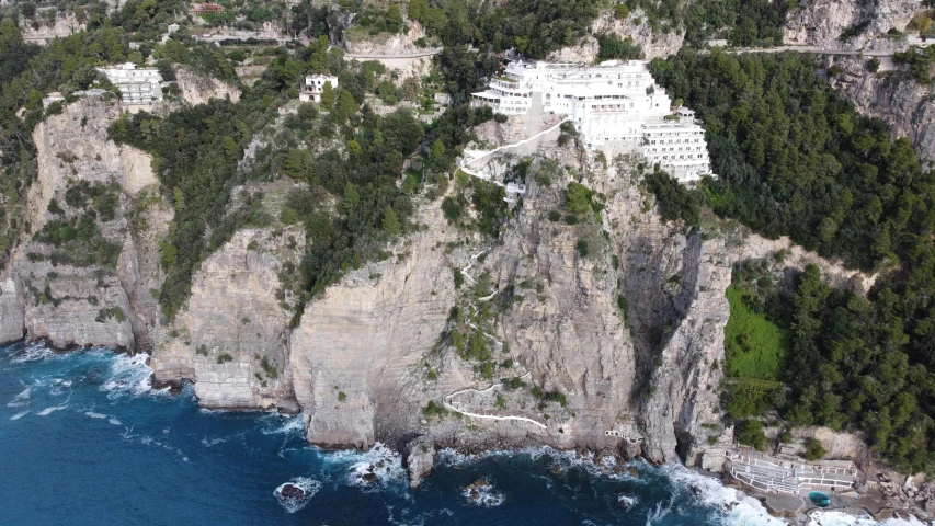 an aerial view of a resort on the cliff above the water