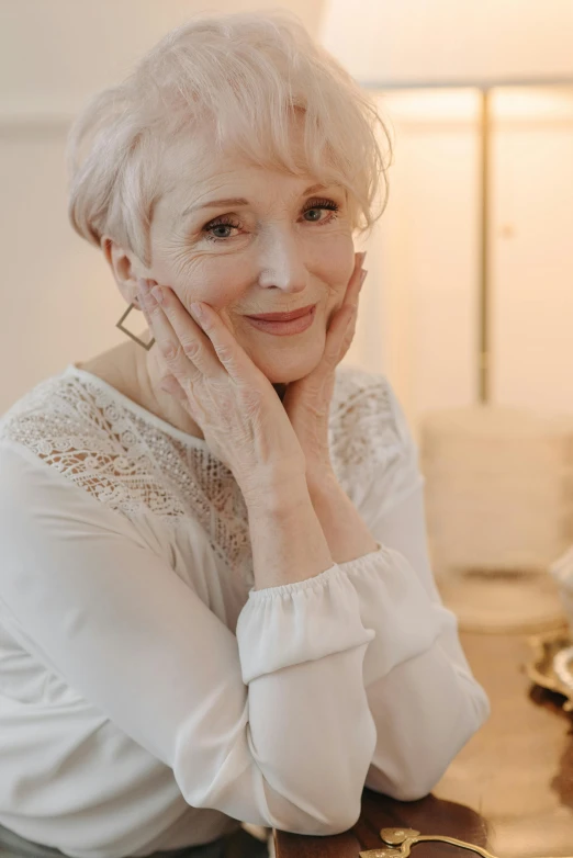 a woman in white shirt with her hand under her face