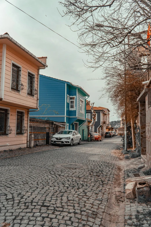 an old cobblestone street is filled with cars and houses