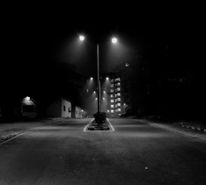 two streetlights on poles in a dark road