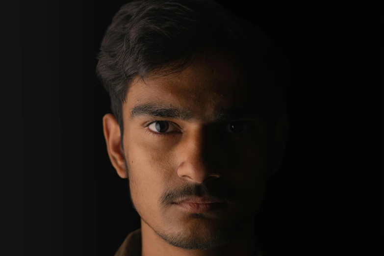 a young man staring straight ahead on black background