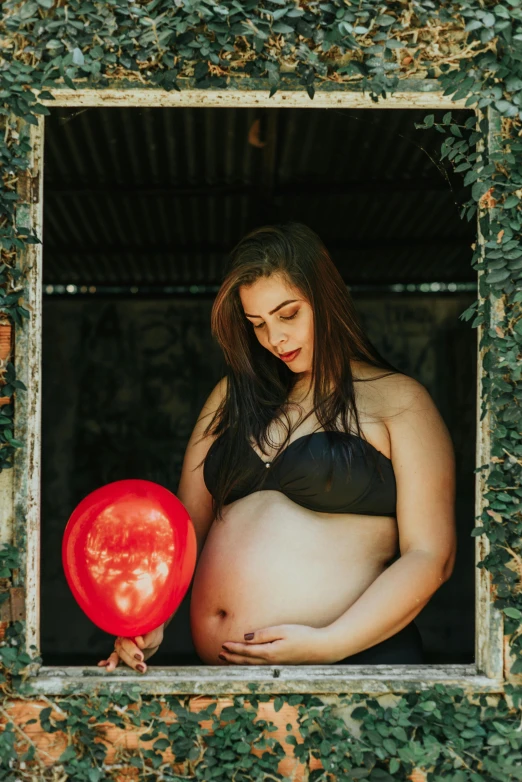 a pregnant woman holding a balloon in the window