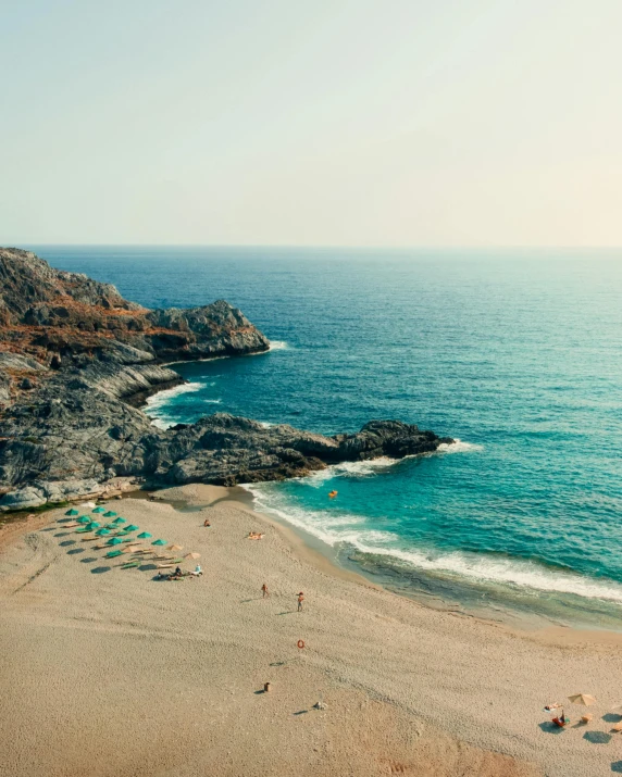 a sandy beach sitting next to a rocky coast under a blue sky