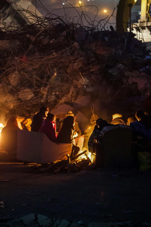 some people sitting around a big fire pit at night