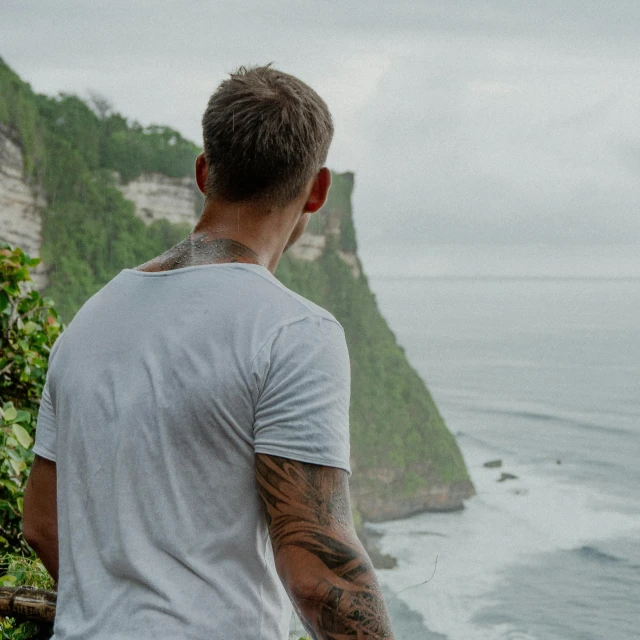 a man in white shirt looking at the ocean