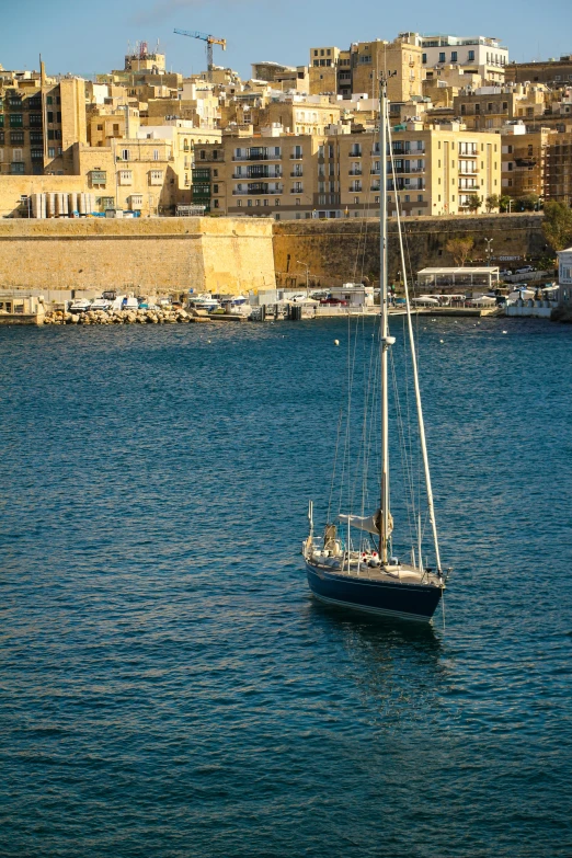 a small sailboat out on the open water in front of a city
