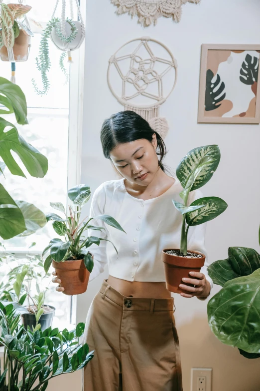 a woman stands in a room with potted plants