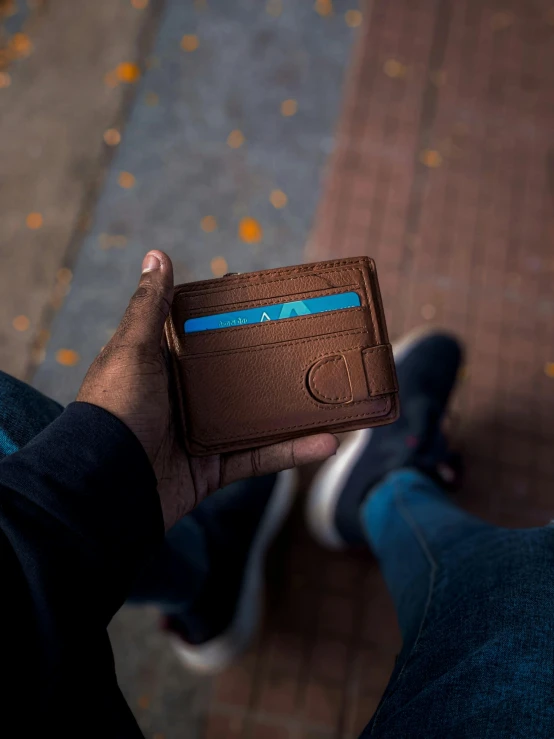 a man holds a wallet in front of his legs