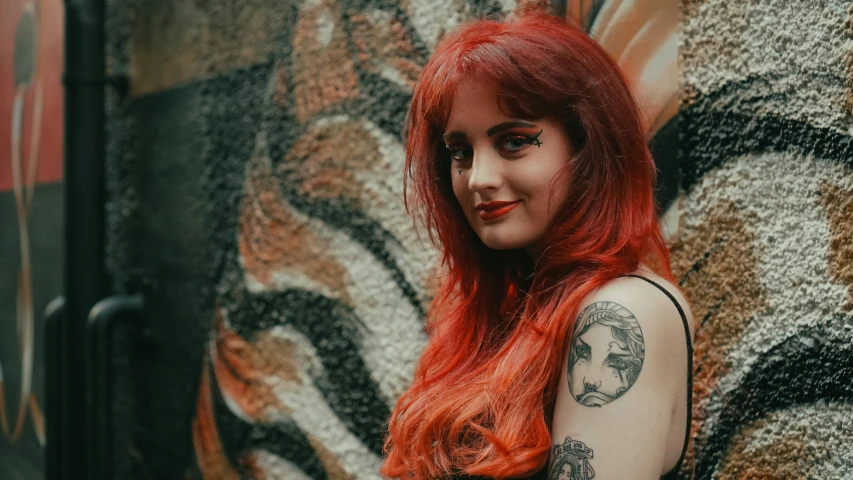 a woman with long red hair and tattoos posing