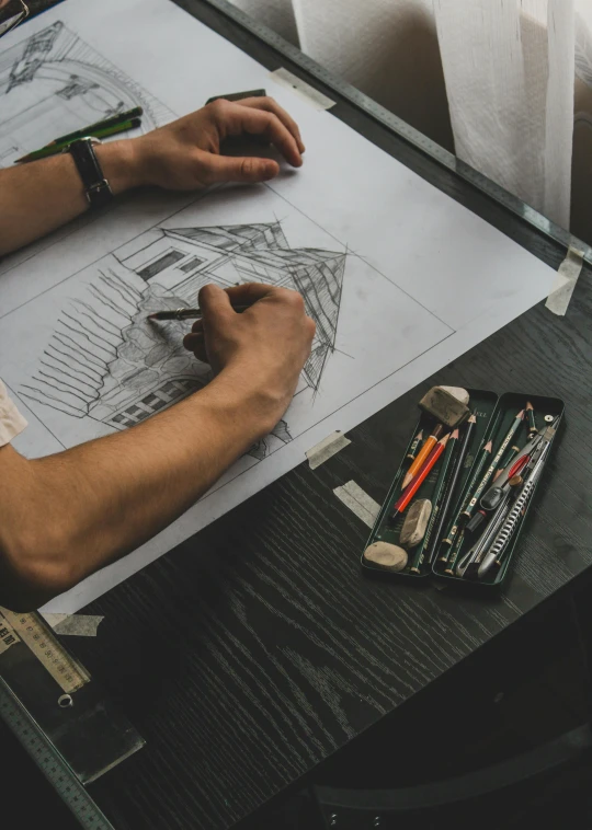 a man is sitting down drawing on a piece of paper