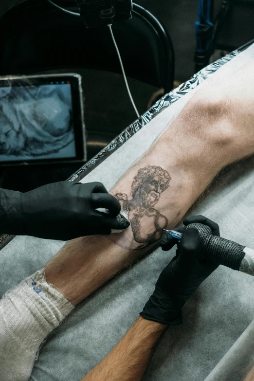 someone is getting a tattoo on their leg