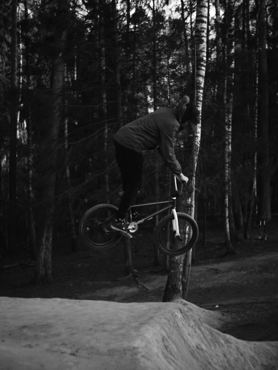 person on bike doing jump with trees in background